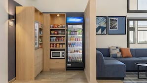A kitchenette with a microwave, shelves with snacks, and a beverage fridge. - City Express by Marriott Bemidji (Bemidji)