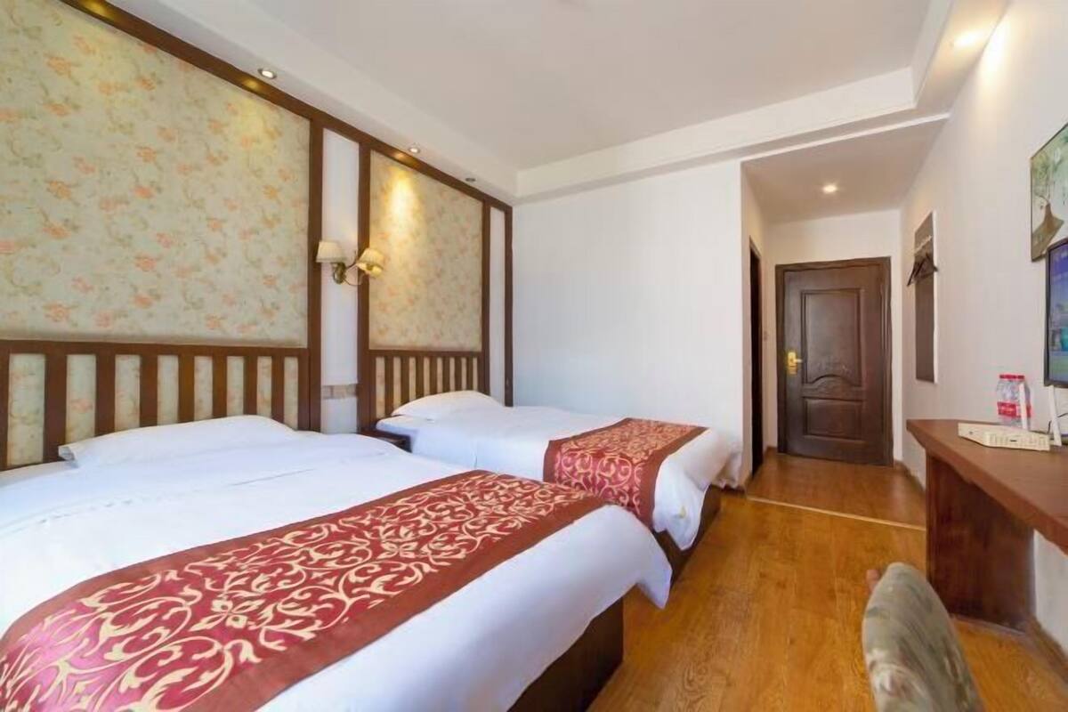 A hotel room with two beds, wooden headboards, and a wooden floor.