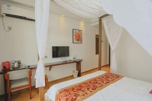 A bedroom with a bed, a desk, a television, and a wall-mounted air conditioner. - Huatianju Inn (Zhangjiajie)