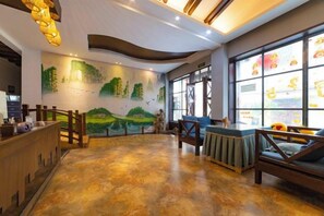 A lobby with a reception desk, seating area, and a mural of a landscape. - Huatianju Inn (Zhangjiajie)