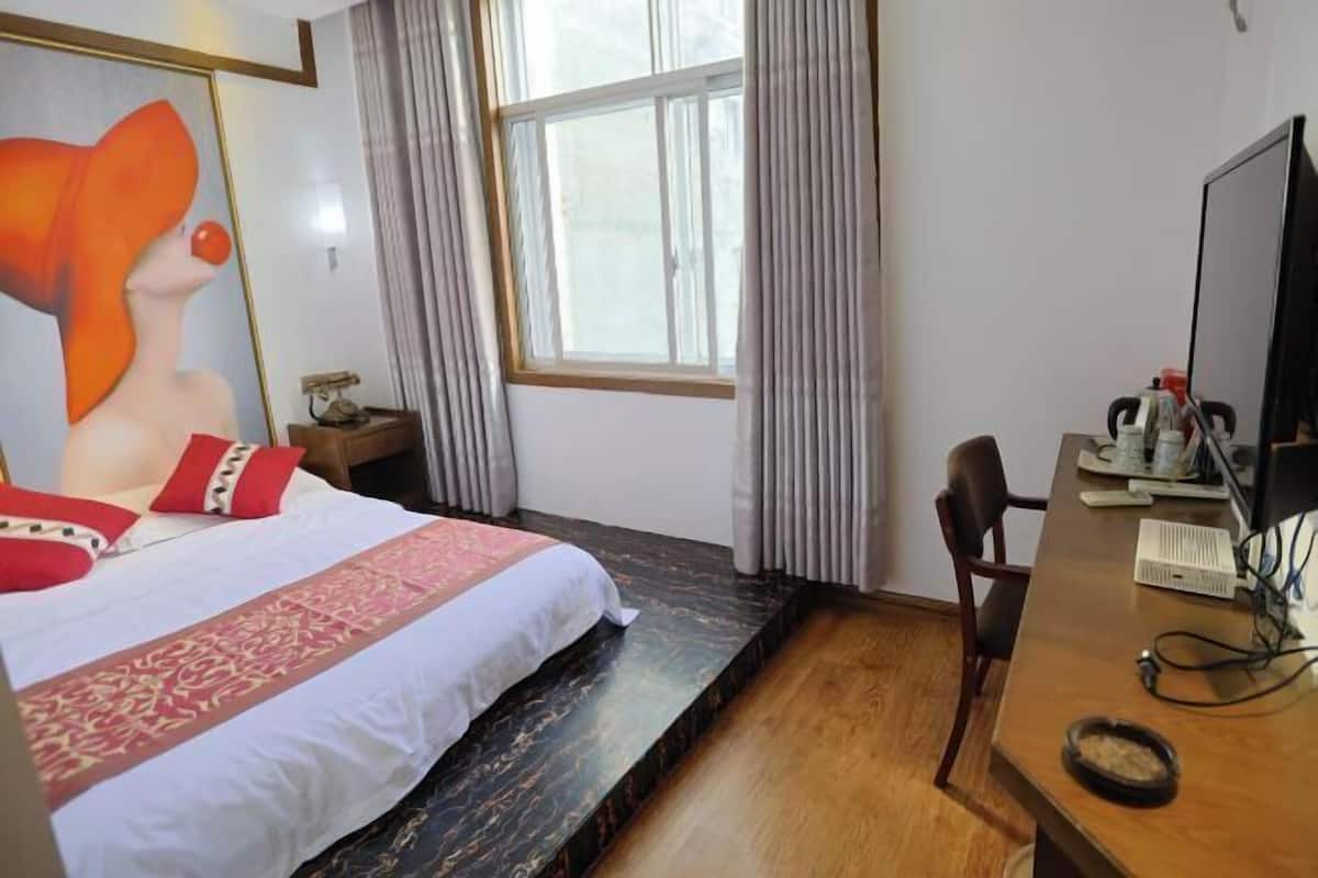 A hotel room with a bed, a desk, a computer, and a window with curtains.