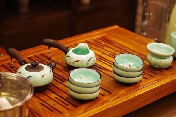 A wooden tray with a teapot, a teacup, and a cup of tea. - Huatianju Inn (Zhangjiajie)