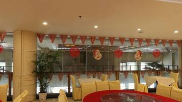 Un comedor con mesas redondas, sillas amarillas y detalles rojos.