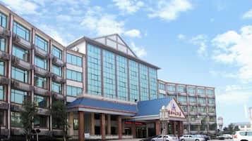 Un hotel con fachada moderna, una entrada destacada y un estacionamiento.