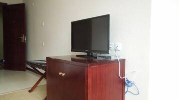 A wooden cabinet with a television on top, a power outlet, and a door in the background.