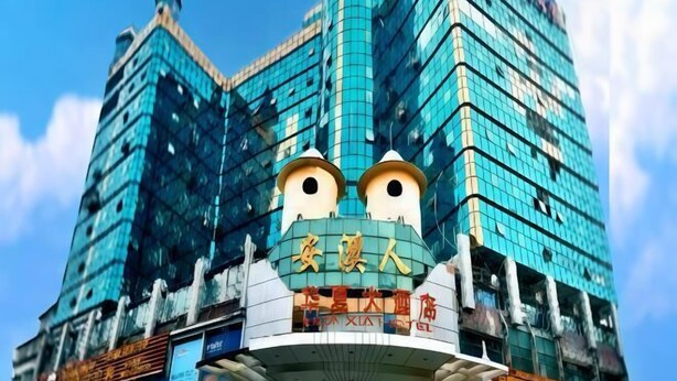 A building with a distinctive facade featuring a large, cartoonish face with eyes and a mouth. - Huaxia Hotel (Anxi)