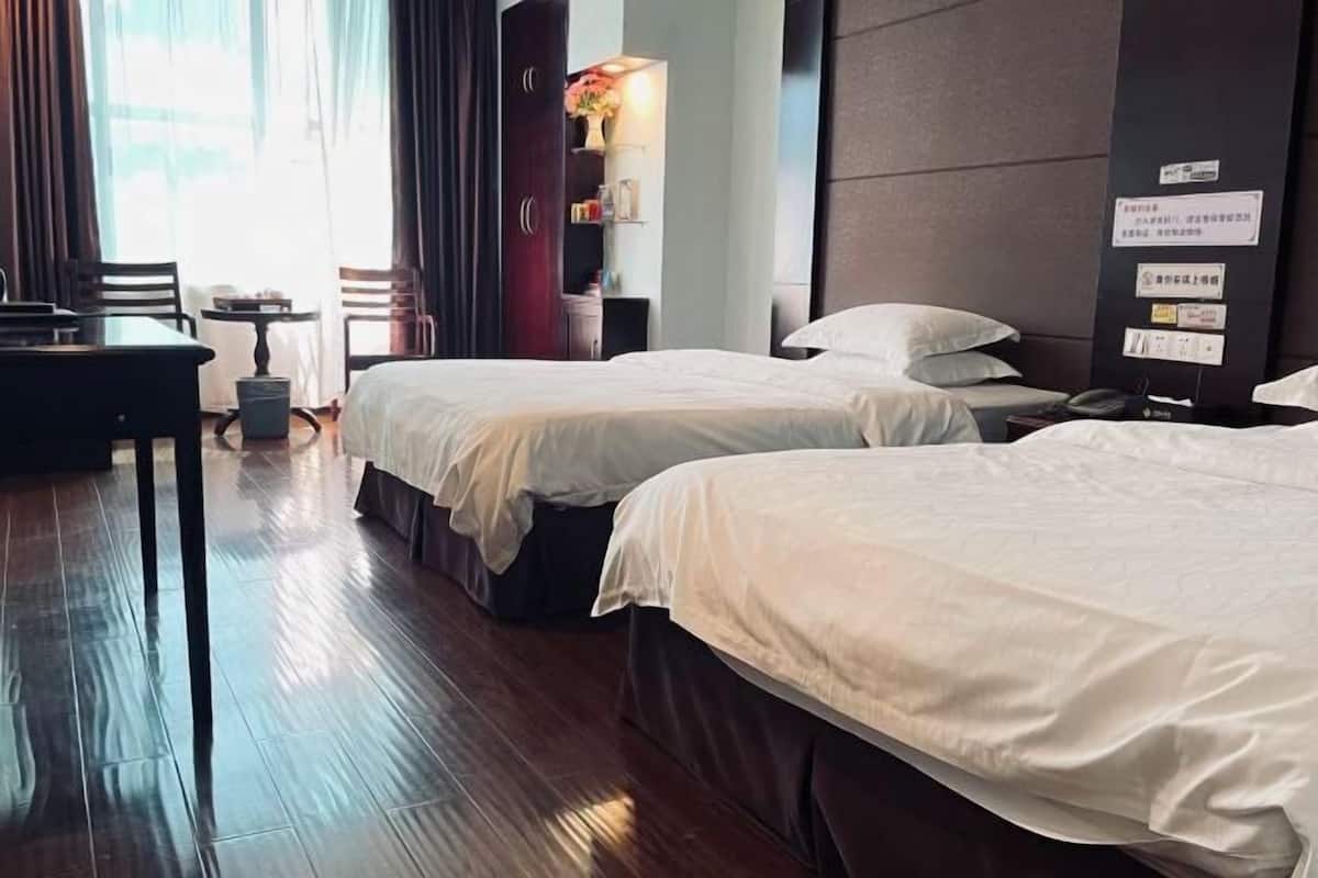A hotel room with two beds, a desk, and a chair.
