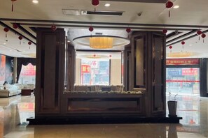A hotel lobby with a reception desk, seating area, and a large window. - Huaxia Hotel (Anxi)