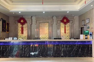 Una recepción con mostrador de mármol, faroles decorativos rojos y un diseño de ventana con motivos.