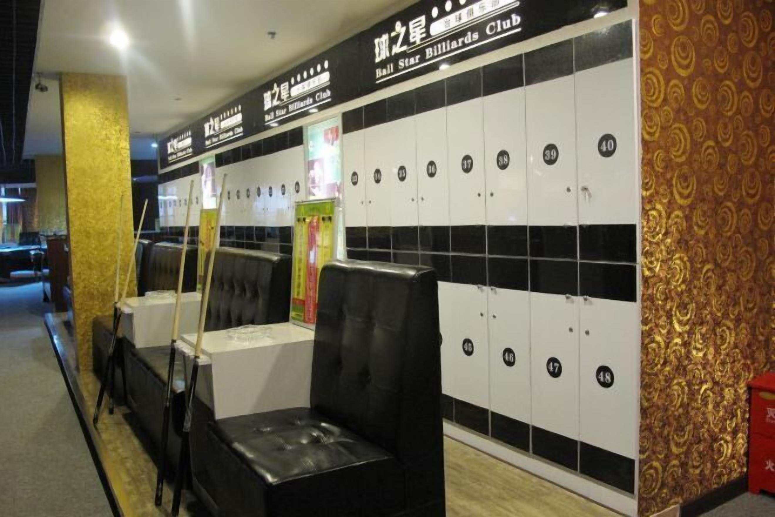 A billiards club with black and white lockers, black cushioned seating, and a patterned wall.