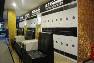 Club de billar con taquillas negras y blancas, asientos acolchados negros y una pared con estampado.
