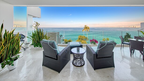 A balcony with wicker furniture, potted plants, and a view of the ocean. - Sayan Tropical 43 New Luxury Oceanfront Condo (Puerto Vallarta)
