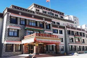 A multi-story building with traditional architectural elements, including decorative trim and a balcony with a red awning. - Xiangqu Garden Hotel (Shannan)