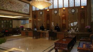 A lobby with a reception desk, seating area, and a chandelier.