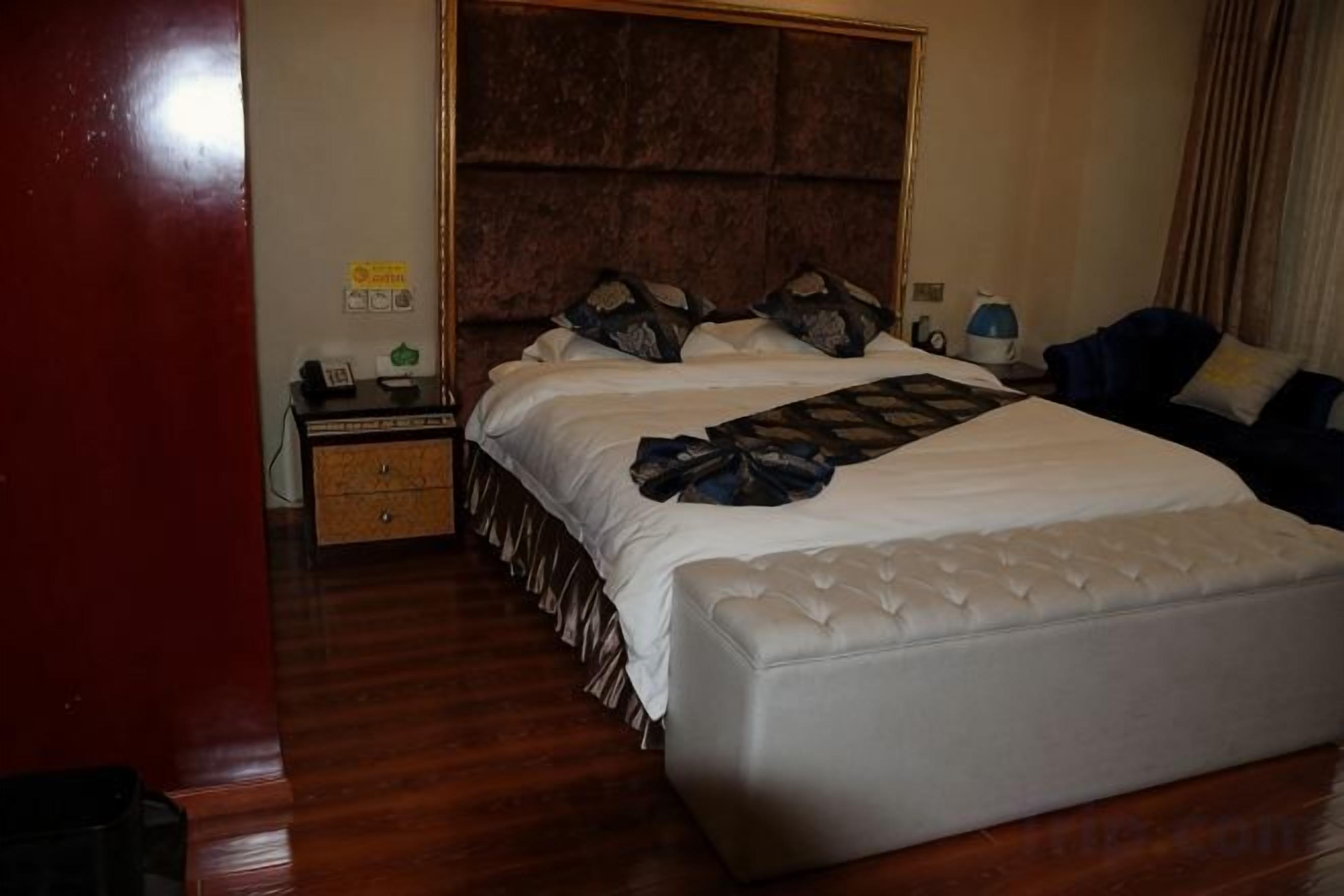 Une chambre d’hôtel avec un grand lit, une table de chevet et une commode.