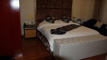 Une chambre d’hôtel avec un grand lit, une table de chevet et une commode.