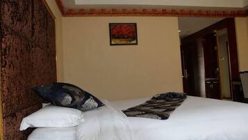 Une chambre d’hôtel avec un lit, un tableau accroché au mur et une porte donnant sur une autre pièce.