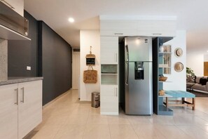 A modern kitchen with a built-in refrigerator, a small dining area with a blue bench, and a living space with a sofa and decorative items. - Large 3BR Apartment with exceptional street views (Ciudad de México)