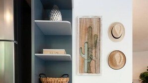 Une cuisine moderne avec une étagère bleue intégrée, un banc en bois et une œuvre d’art représentant un cactus accrochée au mur.