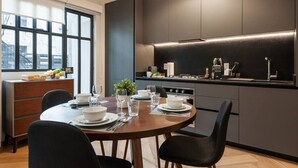 Una cucina moderna con mobili scuri, un tavolo da pranzo per quattro persone e una finestra che offre luce naturale.