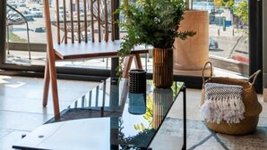 A modern room with a large window, a wooden chair, a glass table, a potted plant, and a woven basket. - Wonderful 2bdr apt with beautiful natural light. (Ciudad de México)