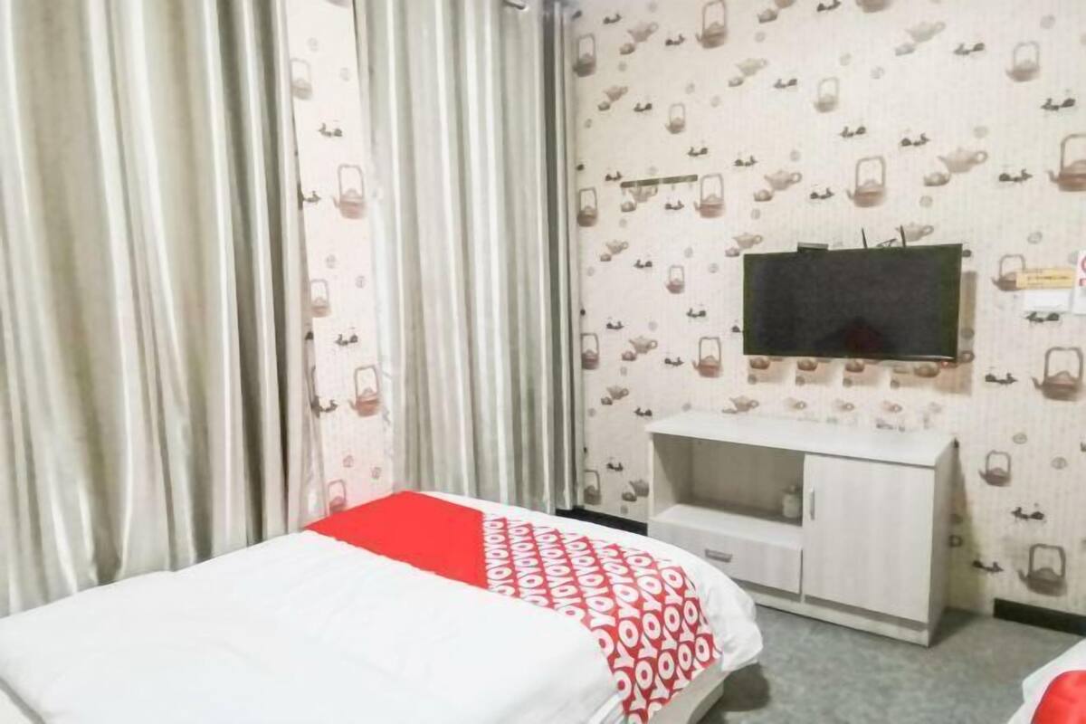 Een hotelkamer met een bed, een aan de muur bevestigde televisie, een kledingkast en behang met een patroon.