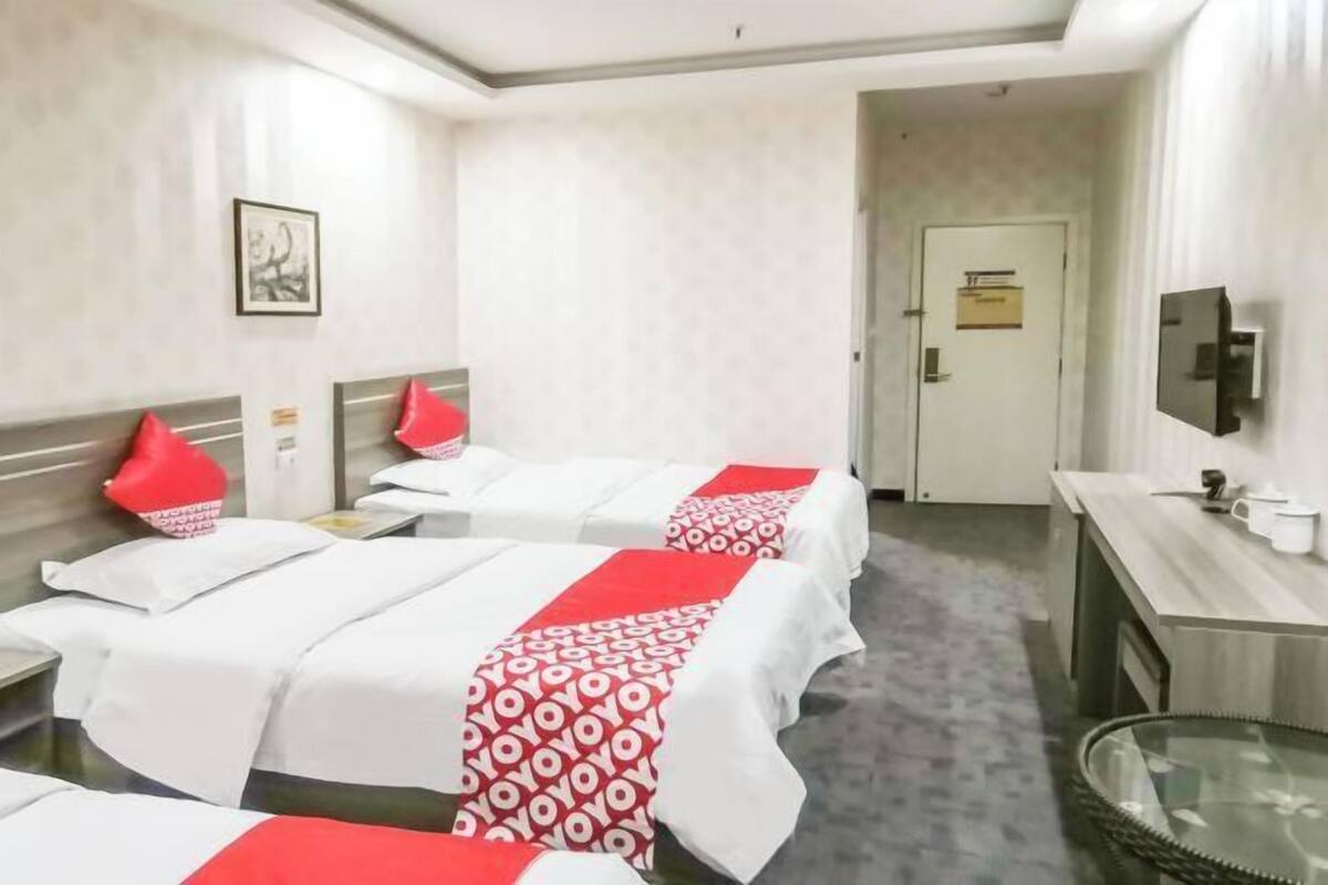 Een hotelkamer met twee bedden, een bureau, een televisie en een deur.