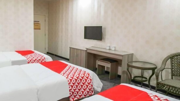 Een hotelkamer met twee bedden, een bureau, een stoel, een televisie en een klein tafeltje.