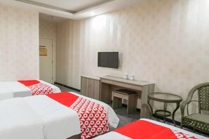 Ein Hotelzimmer mit zwei Betten, einem Schreibtisch, einem Stuhl, einem Fernseher und einem kleinen Tisch.