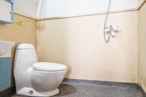 Un baño pequeño con inodoro, lavamanos y ducha.
