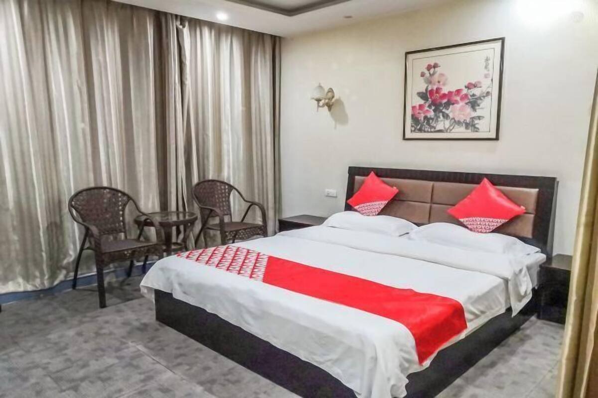 Een hotelkamer met een bed, twee stoelen, een tafeltje en een schilderij aan de muur.