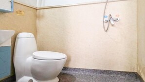 Een compacte badkamer met een wit toilet, een wastafel en een douche.