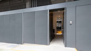A modern building entrance with a wide, yellow safety strip leading to a doorway.