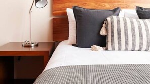 A neatly made bed with a striped blanket, a wooden headboard, and two pillows. There is a nightstand with a lamp beside the bed. - Enjoy skyline/city views from this 17th floor flat (Ciudad de México)
