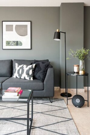 A modern living room with a grey sofa, a black floor lamp, and a small side table with a vase and candle. - Lux large top floor Apt. at The Corner Condesa (Ciudad de México)