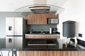 Une cuisine moderne dotée d’un îlot central, d’appareils électroménagers en acier inoxydable et de meubles de rangement en bois.