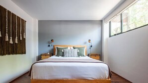 A bedroom with a wooden bed, two bedside tables, a headboard, and a large window. - Modern, Industrial Apartment with Bamboo Garden and Rooftop Terrace (Ciudad de México)