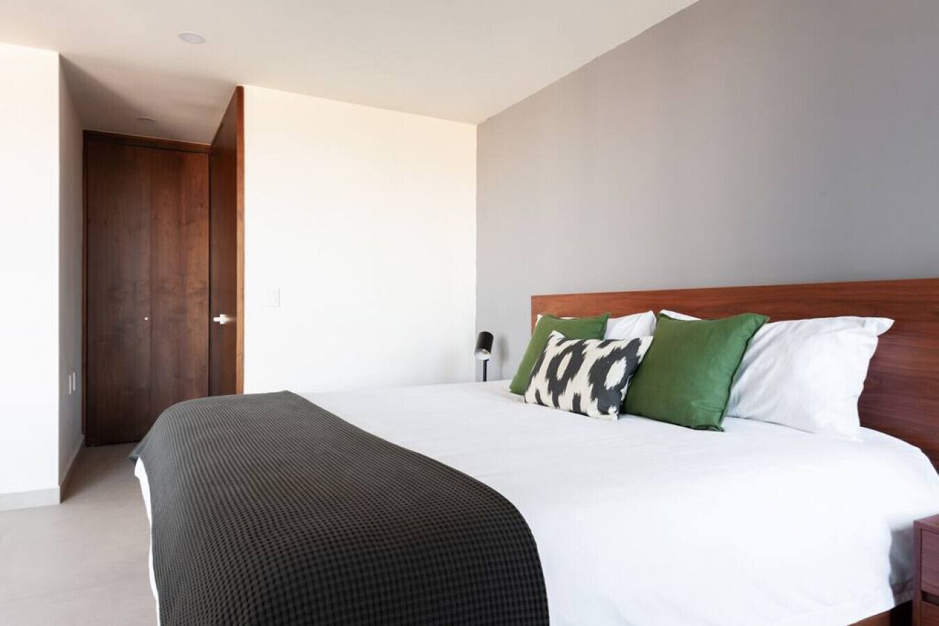 Et moderne hotelværelse med en stor seng, et træhovedgærde og et walk-in closet.