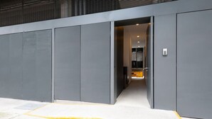 Une entrée moderne, avec une large bande de sécurité jaune qui mène à une porte.