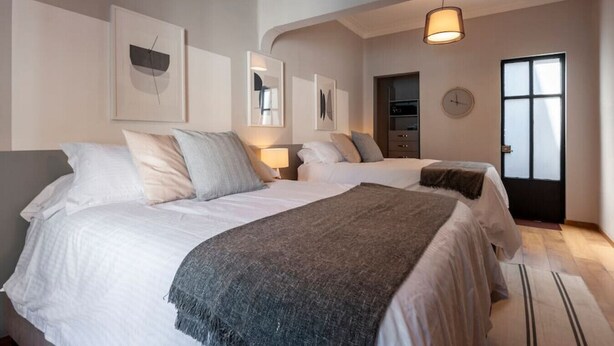 Un dormitorio moderno con dos camas, un armario y un ventanal grande.