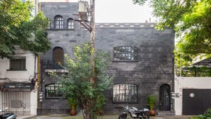 Un edificio de fachada de piedra, una motocicleta estacionada frente a él y un árbol.