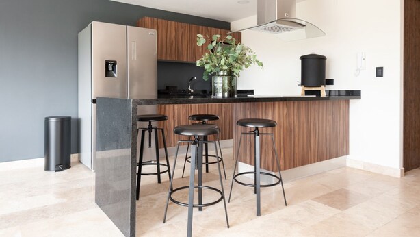 A modern kitchen with a central island, bar stools, a stainless steel refrigerator, and a wooden cabinet. - Bright Luxurious 2 BDR Flat at Corner Condesa (Ciudad de México)
