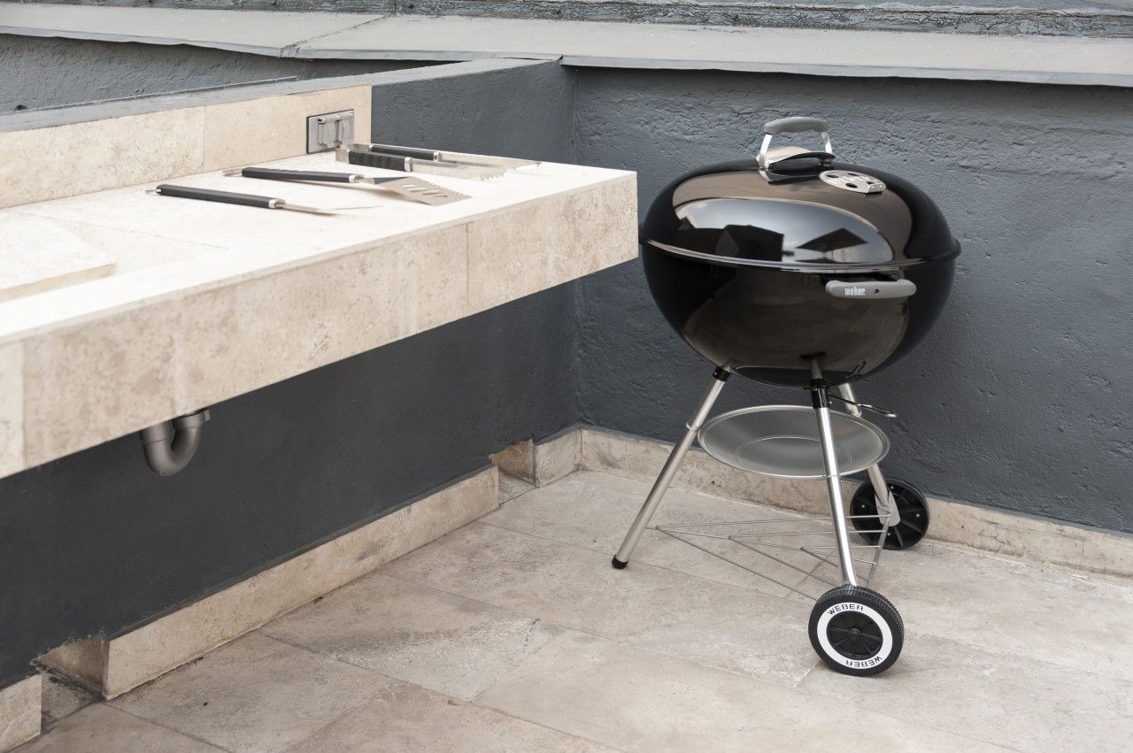 Een moderne buitenkeuken met een ingebouwde barbecue en een spoelbak.