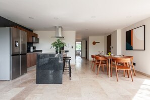 A modern kitchen with a central island, stainless steel appliances, and a dining area with wooden chairs and a table.