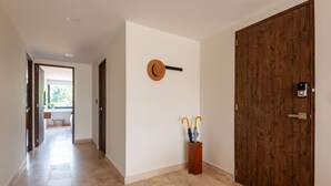 A hallway with a wooden door, a wall-mounted key, and a wooden stand holding two umbrellas. - Bright Luxurious 2 BDR Flat at Corner Condesa (Ciudad de México)