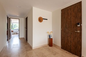 Un couloir avec une porte en bois, un porte-clés fixé au mur et un présentoir en bois contenant deux parapluies.