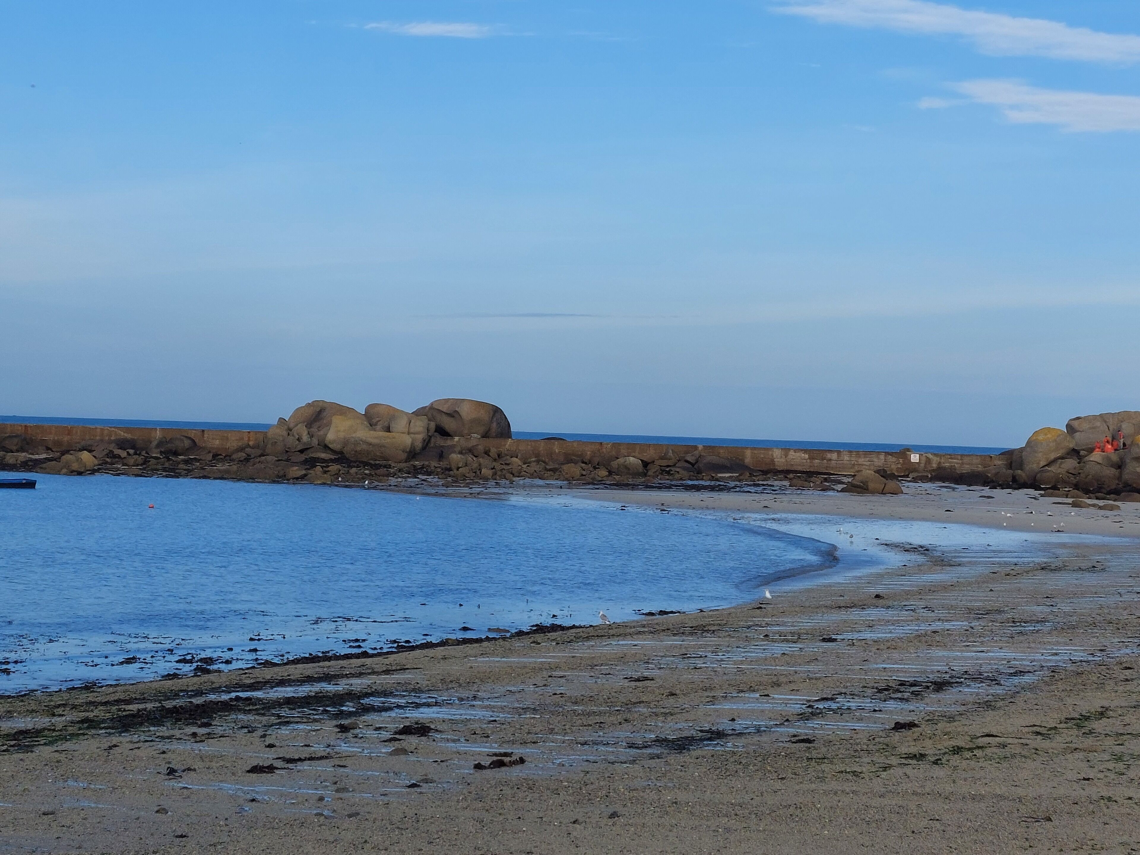 A beach with large rocks, a sandy shore, and calm water.
