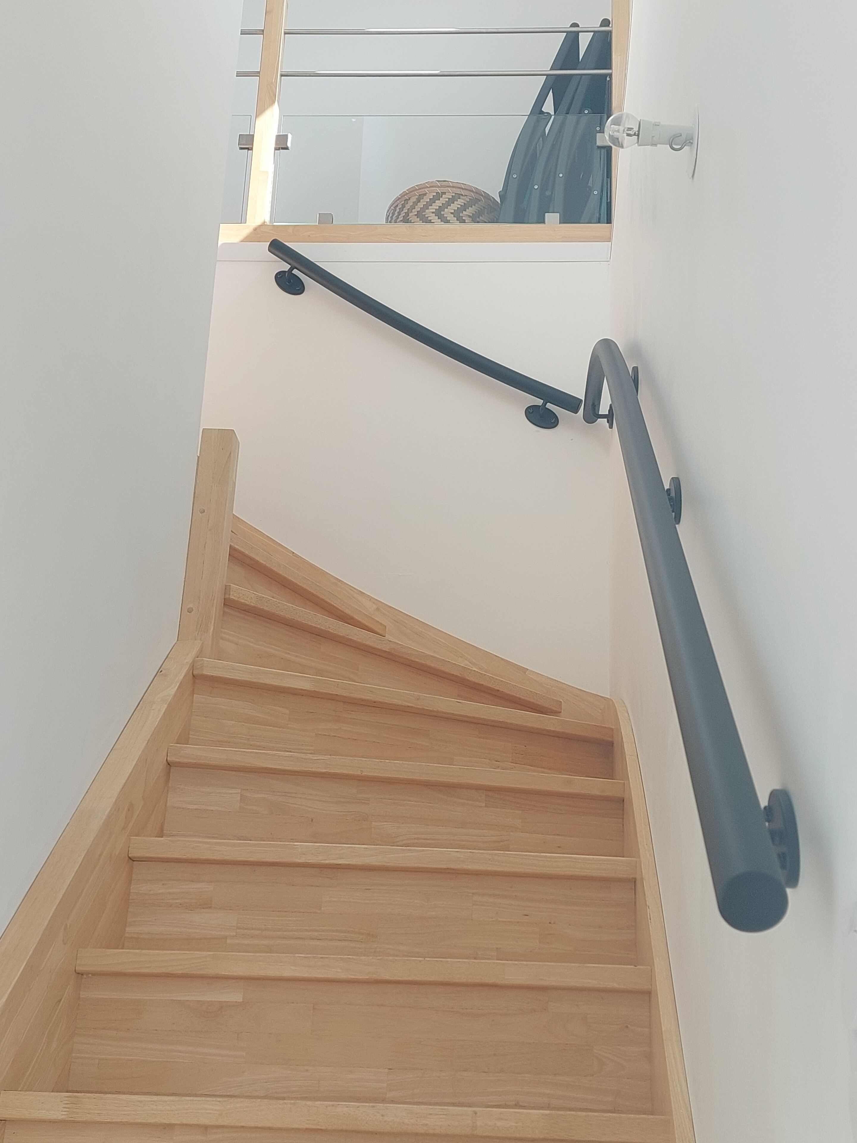 A wooden staircase with a handrail and a glass door at the top.