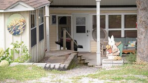 A house with a porch, a welcome sign, and a small garden area. - Beautiful All Season Cottage on Remi Lake (Moonbeam)