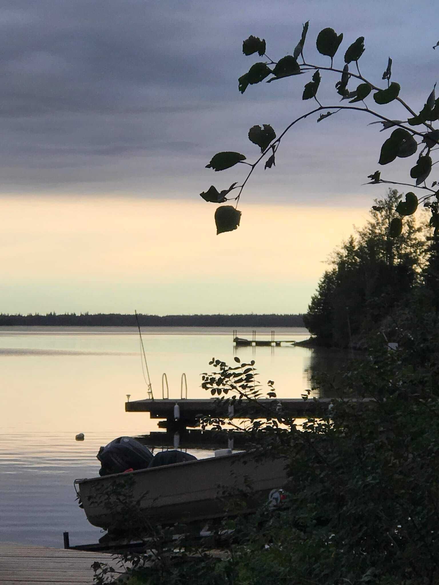 Eine Anlegestelle mit einem Boot und einem ruhigen See bei Sonnenuntergang.